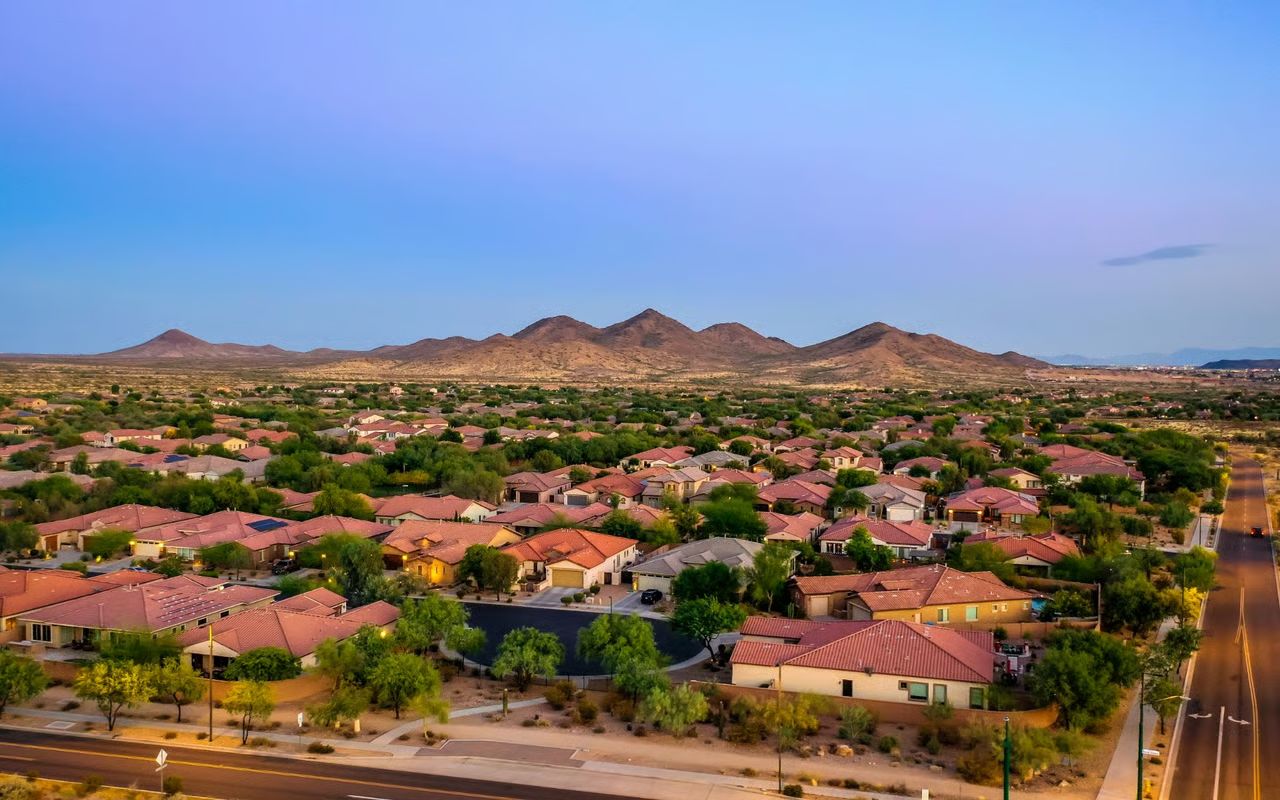 Aerial view of a Cave Creek area neighborhood with desert mountains and red tile rooftops at dusk